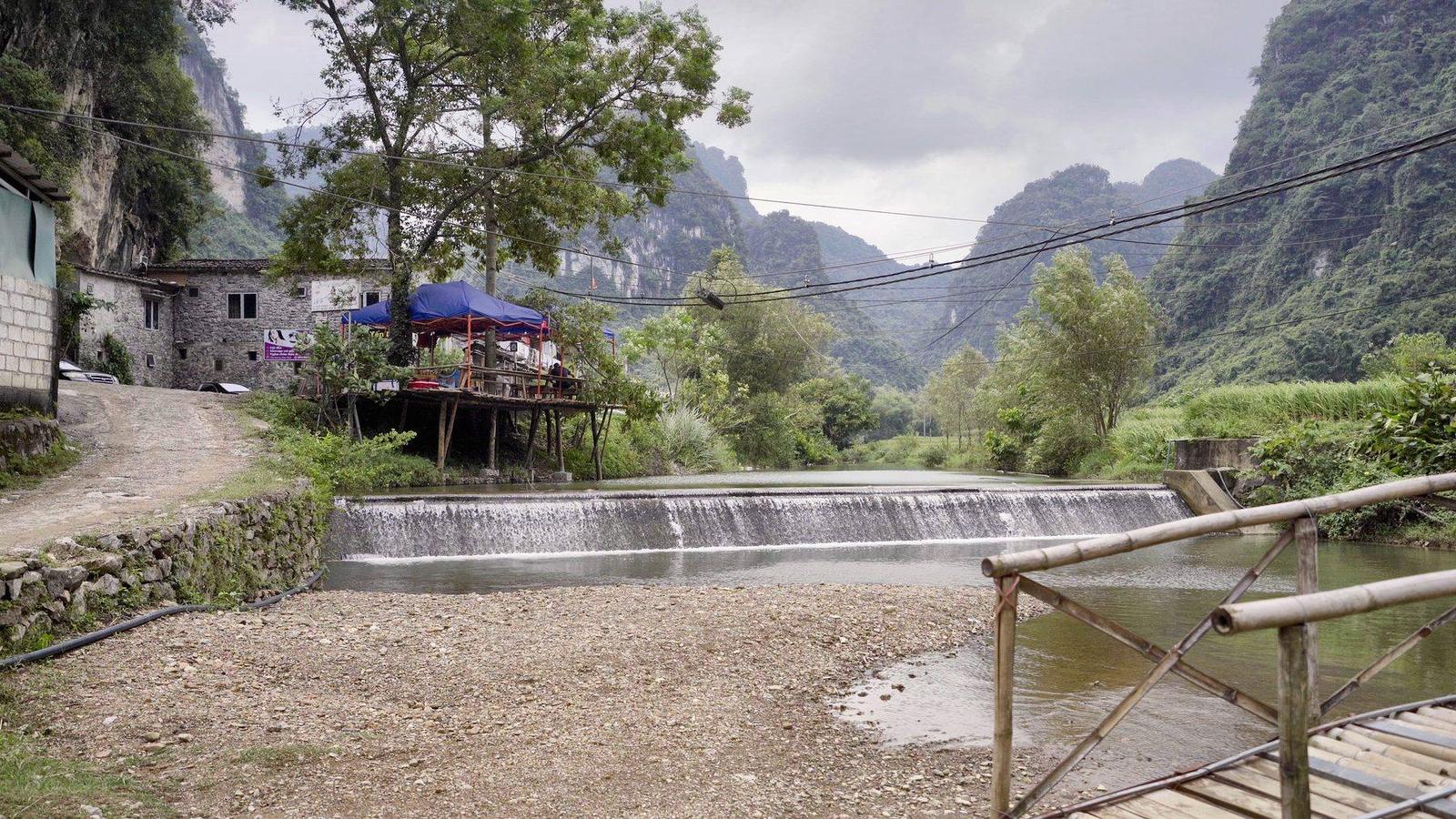 The stream and stone houses of Khuổi Ky village beneath limestone cliffs, Cao Bằng