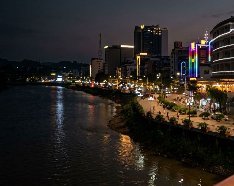 The Bằng Giang river and its lit promenade at dusk, where riverside cafés line the bank in Cao Bằng City